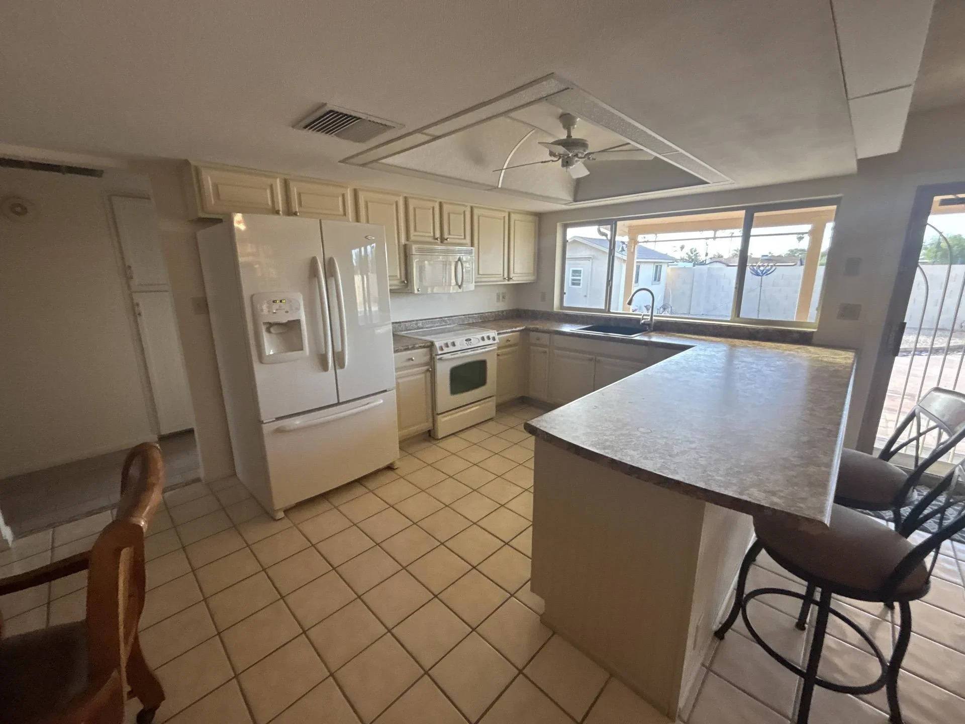 Kitchen remodel with cream cabinets, island, and gray countertops overlooking patio