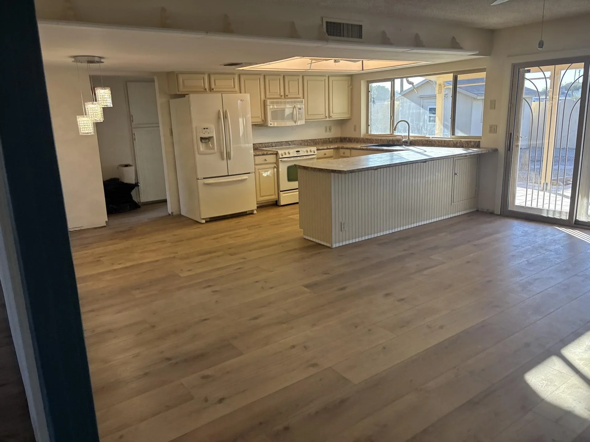 Renovated kitchen with hardwood floors, cream cabinets, granite counters, and island seating